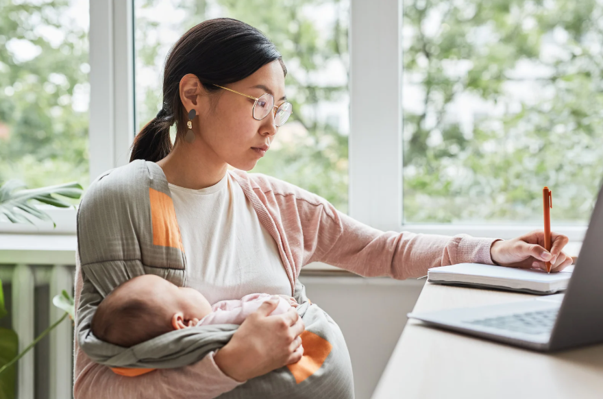 Woman holding baby writing on notepad